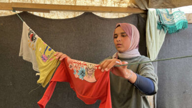 صورة نازحة فلسطينية تحول خيمتها إلى متجر ملابس لإعالة أسرتها