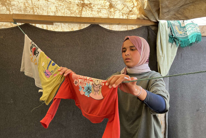 صورة نازحة فلسطينية تحول خيمتها إلى متجر ملابس لإعالة أسرتها