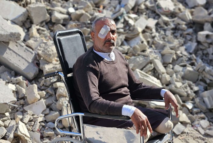 صورة غزاوي أقعدته وحشية القصف يستذكر أولاده الشهداء أمام ركام منزله